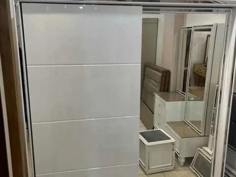 دولاب سحاب بإطار فضي وباب مرآة في غرفة نوم