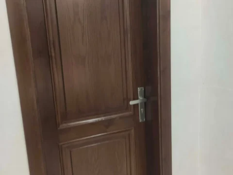باب خشب داكن بحشوتين مقوّستين بعد التركيب